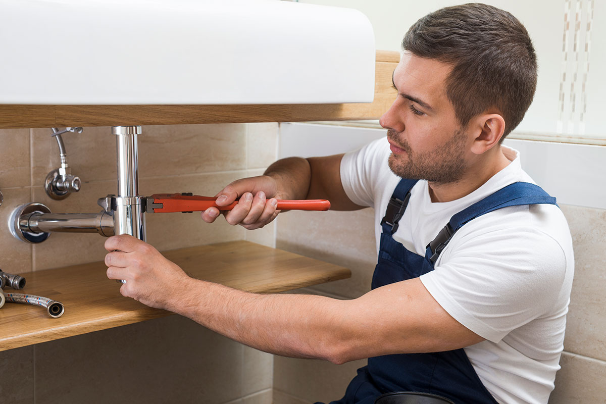 sanitary-technician-using-wrench-sink
